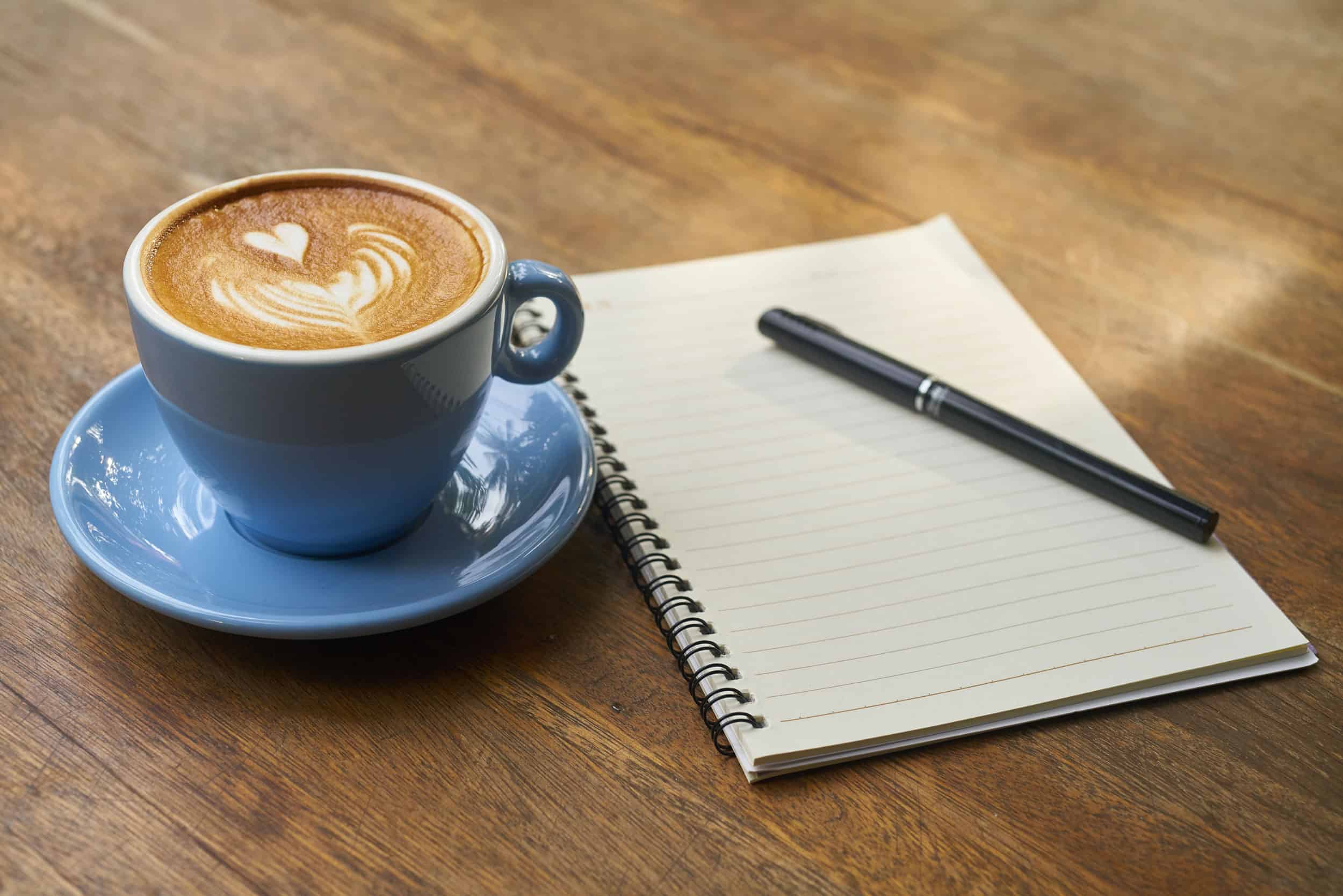 picture of a Hatillo Coffee beverage next to a notebook and a pen to introduce the specialty coffee knowledge category of the website